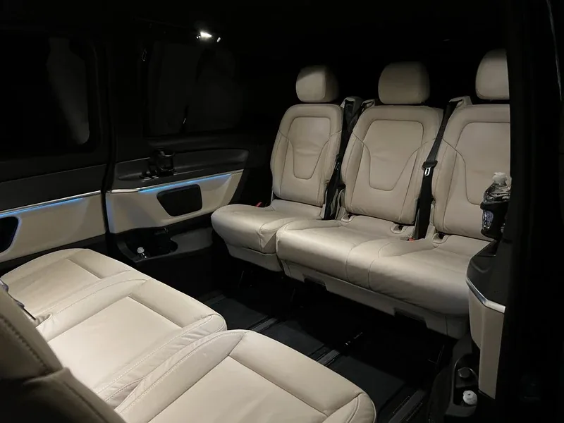 Intérieur Mercedes Classe V Cannes Driver, sièges cuir crème, ambiance lumineuse bleue, tablettes individuelles rabattues