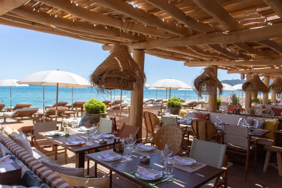 Restaurant de plage à Pampelonne, Saint-Tropez — tables dressées face à la mer sous la pergola